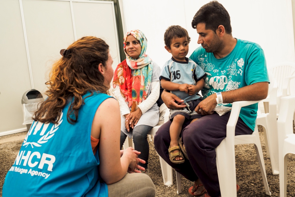 An Afghan family talks with UNHCR staff while waiting to collect their newly issued ID’s by the Greek Asylum Service. © UNHCR/Achilleas Zavallis