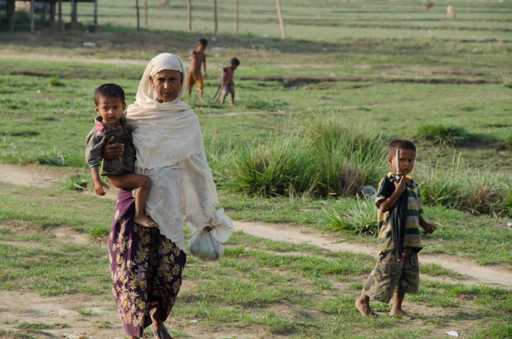 A woman and two young children walk on the outskirts of Say Tha Mar Gyi IDP camp, near Sittwe, Myanmar, on May 26, 2015.