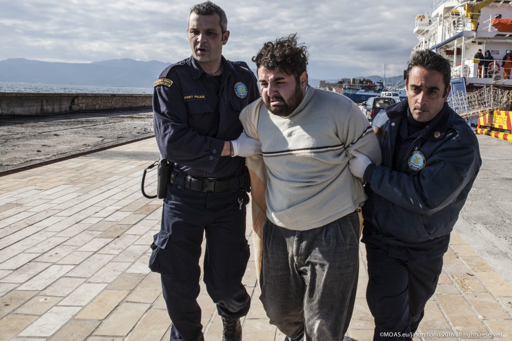 Suspected smuggler Ak Oskart being taken away by police in Samos, Greece. Photo: Jason Florio/MOAS.