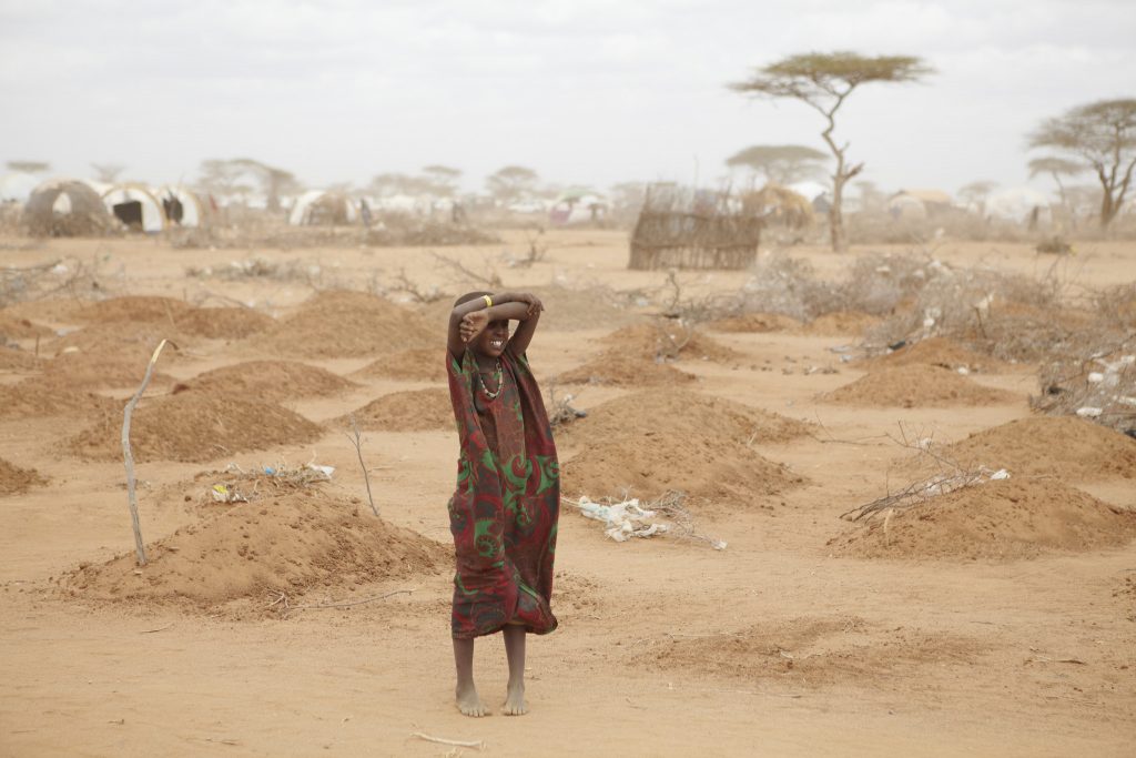 A young girl stands amid the freshly made graves of 70 children, many of whom died of malnutrition, outside Dadaab refugee camp. Photo: Andy Hall/Oxfam.