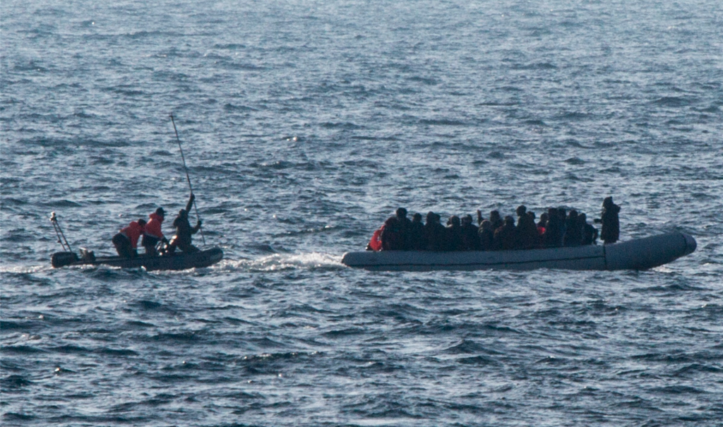 A Turkish coast guard about to strike the back of a migrant dinghy with 40 people on board, including 15 children. Photo: Jason Florio